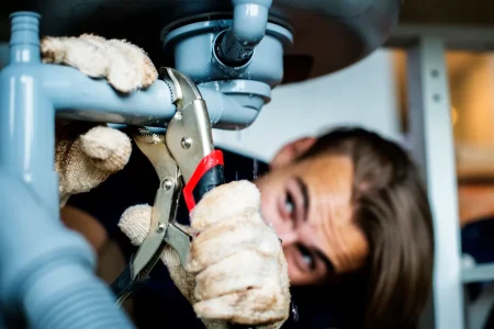 Handwerker zieht ein Abflussrohr mit einer Zange fest, um eine Undichtigkeit zu beheben